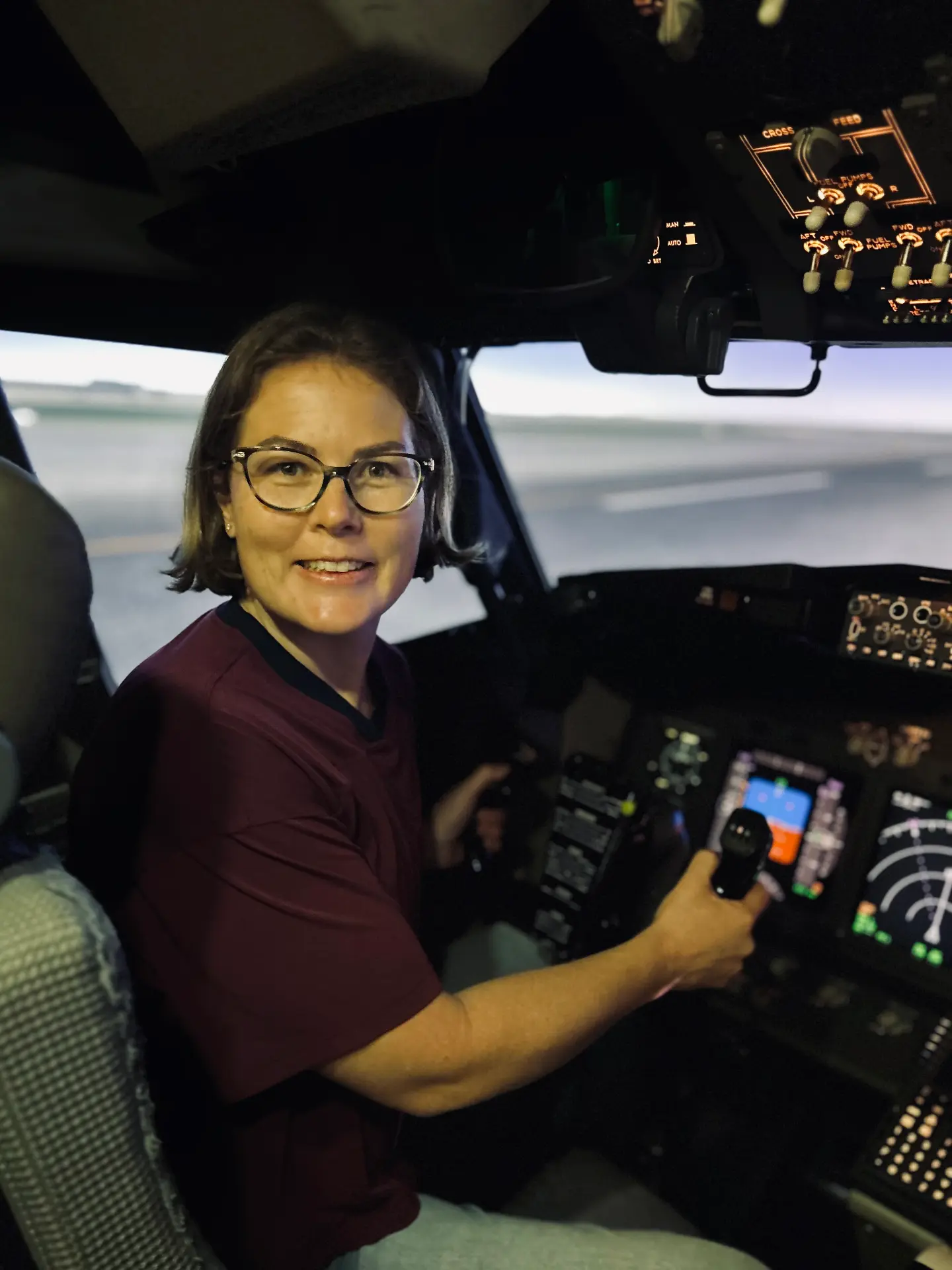Dr Ruth Parsell seated in a flight simulator cockpit holding the controls